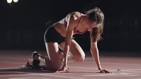 One-woman-in-the-dark-at-the-stadium-is-preparing-to-start-a-race-on-the-track.-Slow-motion-woman-starts-from-hunger-strikes-in-the-stadium-in-the-dark